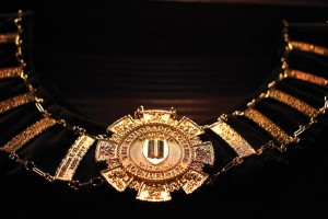 The Colorado College “chain of office,” presented to President Jill Tiefenthaler at her inauguration this year, was created by Harry Hamill ’84, a geology major while at CC. He is now an artist and a well-known creator of jewelry and medallions. Susan Smith Burghart ’77 provided the funding for the piece. The chain of office is one of the oldest symbols of authority. It is intentionally a heavy collar, to represent the weight of office. Its links, forming a circle, symbolize unity, wholeness, returning cycles, and infinity. The chain links past to present, and the CC presidential chain of office features the names of all of its presidents. The chain is meant to be worn by the president at all official academic events.